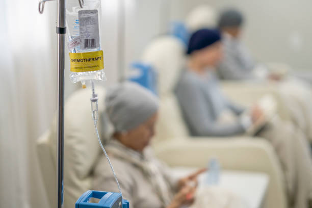 Trois femmes sont assises dans des fauteuils individuels alors qu'elles reçoivent leur chimiothérapie par voie intraveineuse. Elles sont toutes habillées confortablement et portent un foulard pour se réchauffer pendant qu'elles s'adonnent à l'activité qu'elles ont chacune apportée pour s'occuper.